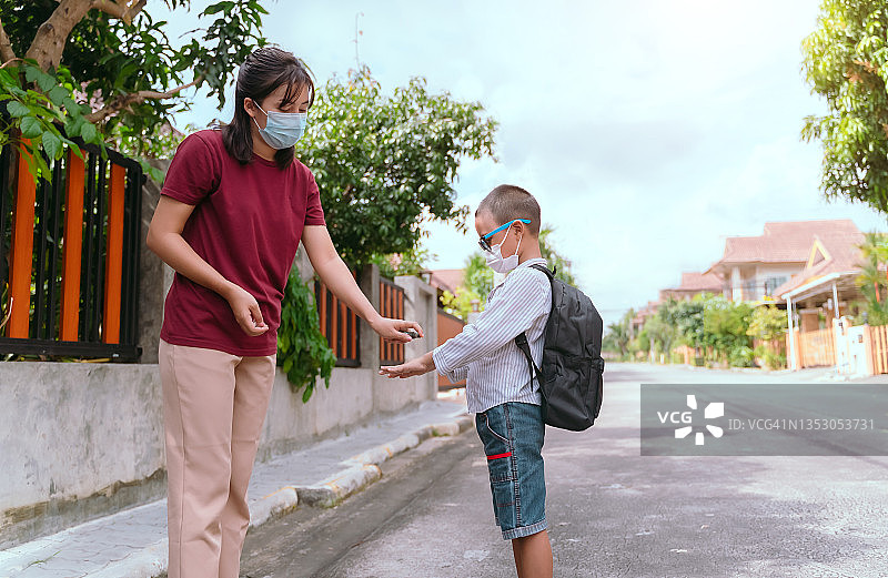 预防新冠病毒和病毒感染的概念。母亲在女儿上学前用洗手液洗手图片素材