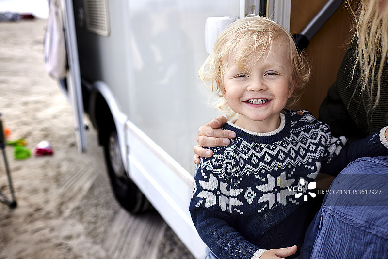快乐的蹒跚学步的男孩和母亲在露营车的肖像图片素材