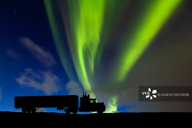 一辆半挂车的剪影在道路上的北极光的背景下图片素材