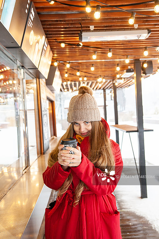 微笑的女人与一杯外卖咖啡在冬天的城市图片素材
