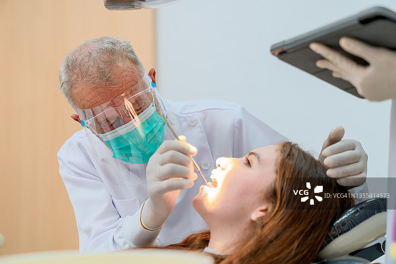 在手术室里，一群牙医正在为女孩进行牙齿治疗。图片素材