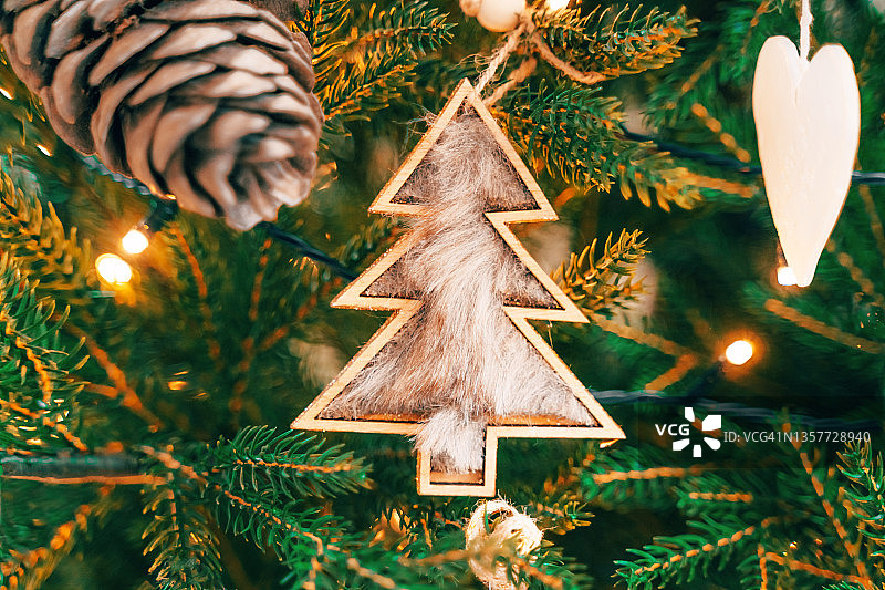 圣诞树毛茸茸的工艺和木制小摆设挂在冷杉树上图片素材