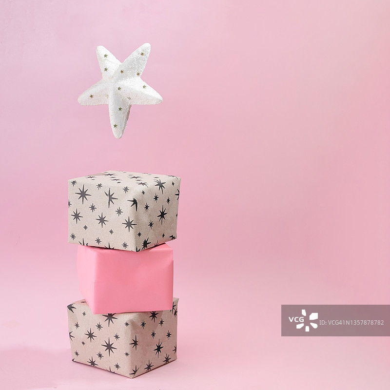 有星星和圣诞树顶的礼品盒。新年present concept idea。柔和的粉色背景。节日和生日设计理念图片素材