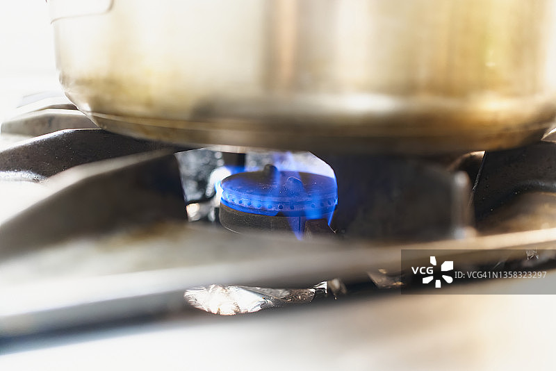 在专业厨房里，在现代煤气炉上的不锈钢煎锅里制作食物的特写图片素材