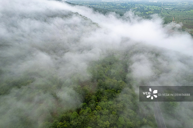 鸟瞰弯曲的乡村道路与绿色的夏季雾森林在泰国。图片素材