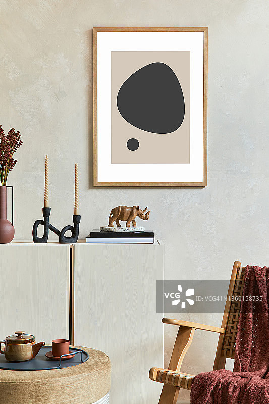 时尚的现代客厅内部组成与模拟海报框架，木制餐具柜，藤扶手椅和波西米亚启发配件。模板。图片素材