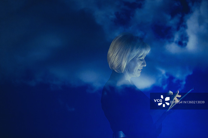 女商人带着数码平板电脑对抗蓝天白云图片素材