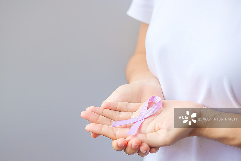 世界癌症日(2月4日)，妇女手握薰衣草紫丝带，为生活和疾病的人们提供支持。医疗保健与医疗概念图片素材