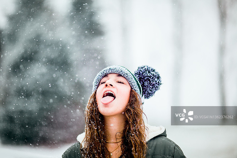 一个十几岁的女孩在后院享受着飘落的雪花图片素材