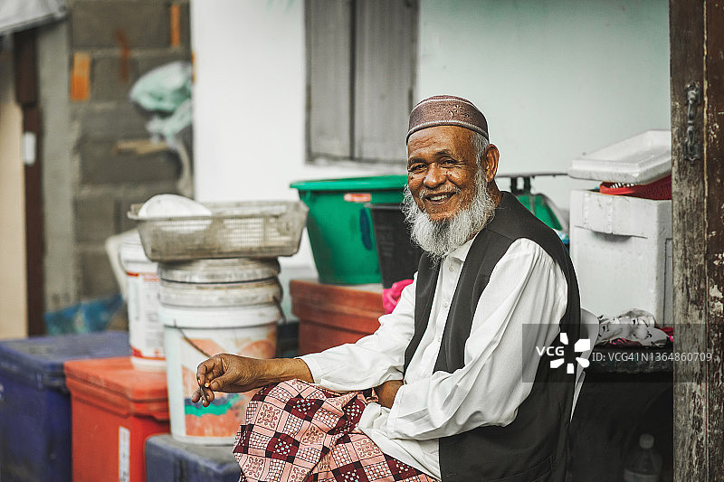 微笑的老穆斯林老人的肖像与灰色的胡子。穿着传统的服装和帽子图片素材