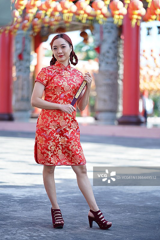美丽的亚洲妇女在中国传统的旗袍旗袍服持扇图片素材
