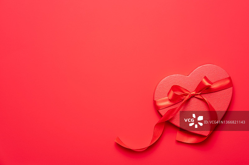 女性手握红色背景上的红心礼盒。情人节组成图片素材