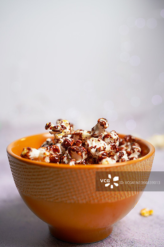 一份爆米花放在橙碗里，背景模糊——巧克力爆米花图片素材