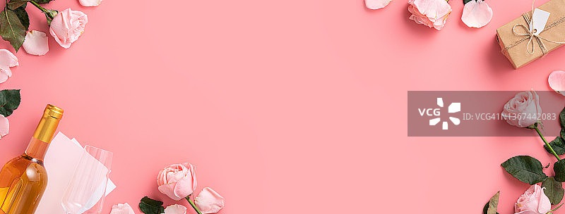 情人节礼物，葡萄酒和粉红色的玫瑰花束在粉红色的背景。图片素材