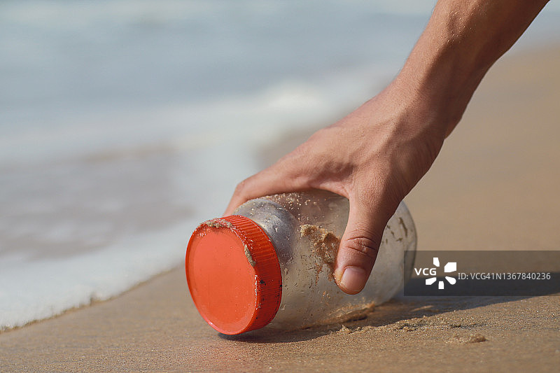 在海边用手捡塑料瓶。图片素材