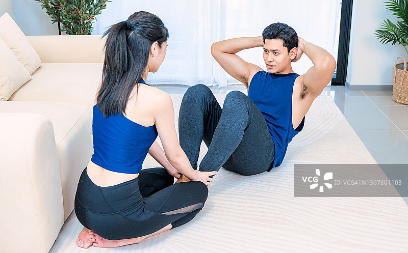 一对快乐的年轻夫妇在隔离室做瑜伽。伸展运动。锻炼。强壮美丽的运动健身夫妇穿着运动服在家图片素材
