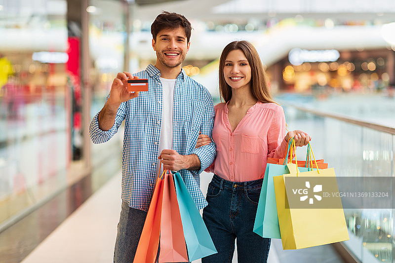 一对夫妇在超市购物，拿着购物袋，手里拿着信用卡图片素材