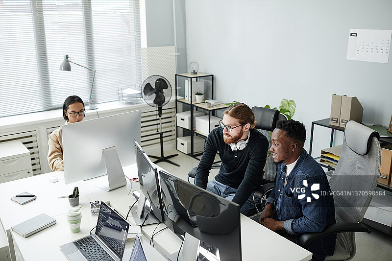 两个年轻的程序开发人员穿着休闲服坐在电脑显示器前图片素材