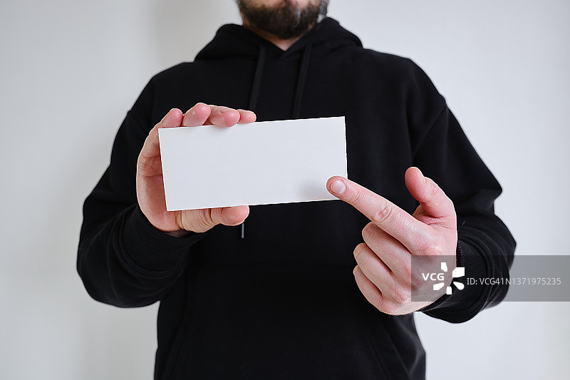 白色的空牌在一个男人的手中在黑色的背景上。放置文字和广告。名片图片素材
