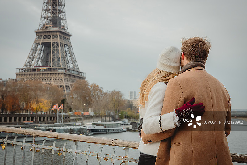 法国巴黎，一对情侣站在塞纳河上拥抱，看着埃菲尔铁塔的后视镜图片素材