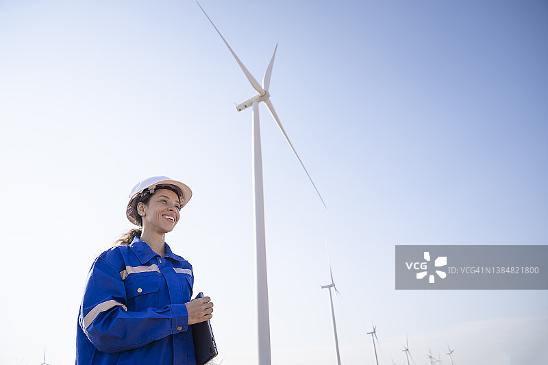 女工程师微笑着站在风力涡轮机农场图片素材