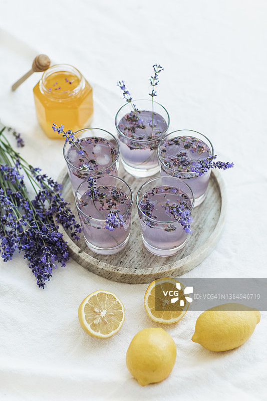 蜂蜜、加冰玻璃杯、柠檬汁和薰衣草鸡尾酒放在厨房桌子上。图片素材
