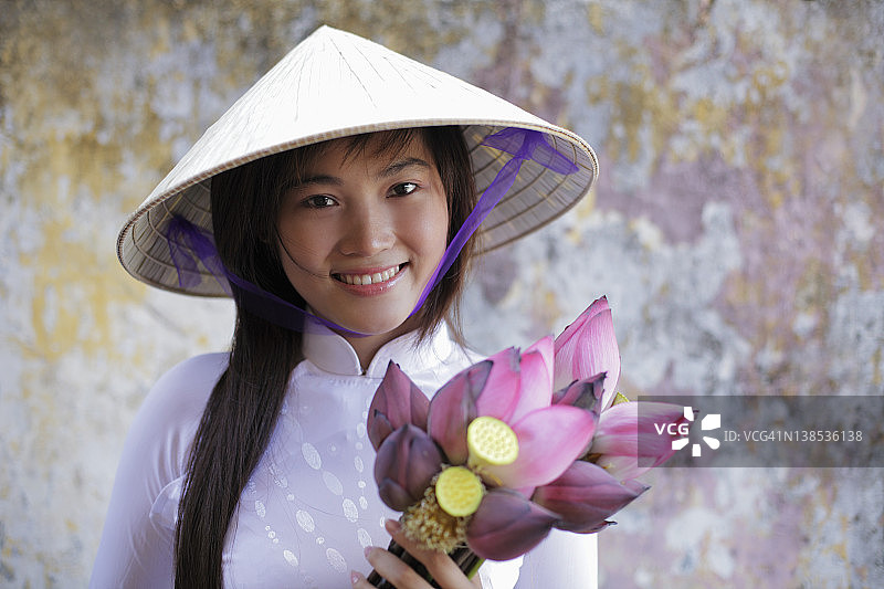 年轻女子身穿越南传统服饰，手持荷花图片素材