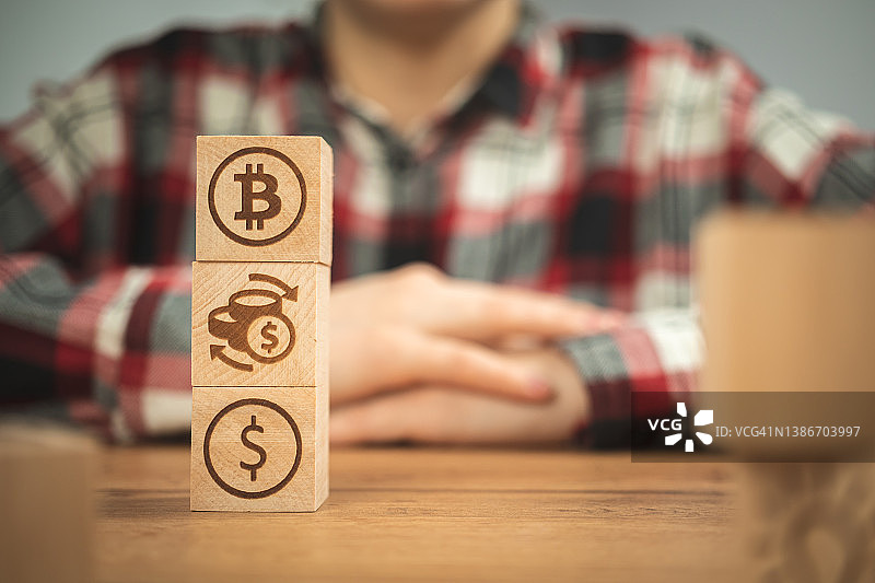 比特币在手中的木头立方体上交换美元符号。概念加密货币和现金背景，木桌图片素材