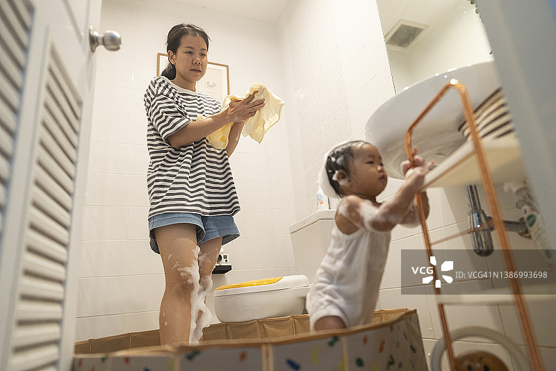 亚洲妈妈和女儿在厕所里玩带淋浴泡沫的小池塘，在家里简单的快乐图片素材