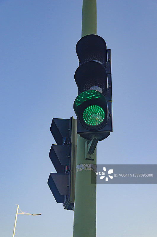 绿色交通灯对着晴朗的天空的低角度视图图片素材