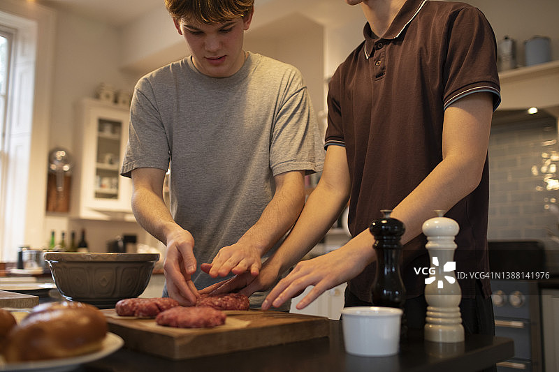 十几岁的男孩在厨房里做汉堡肉饼图片素材