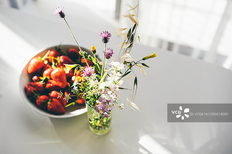 厨房餐桌上的野花和草莓。图片素材