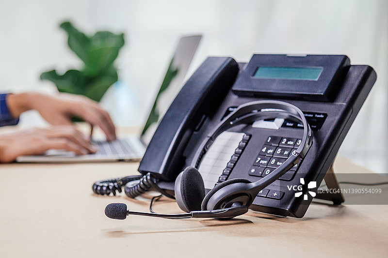 通信支持，呼叫中心和客户服务帮助台。办公室电话设备与VOIP耳机。客户服务支持(呼叫中心)概念。图片素材