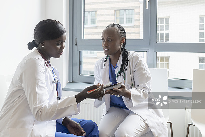 两名女医生在候诊室用数码平板电脑讨论体检结果图片素材