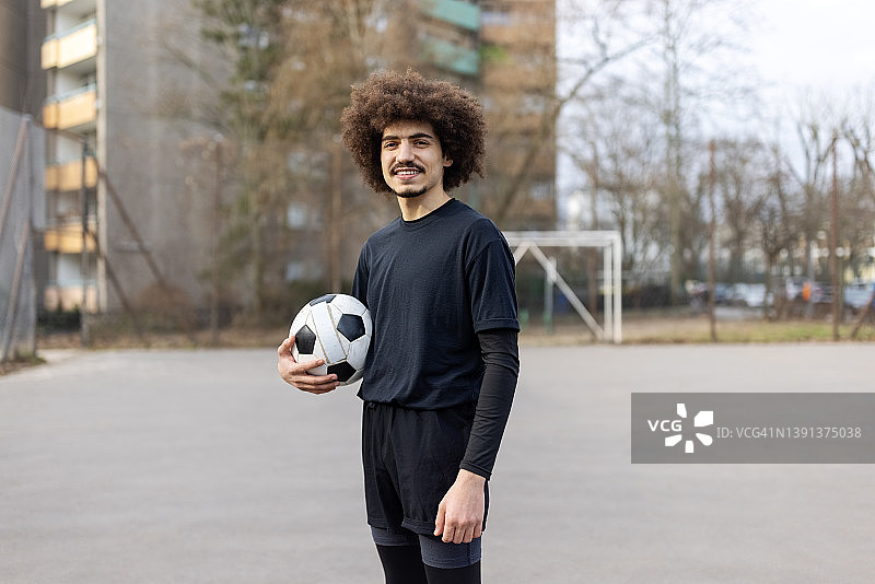 年轻的中东球员在体育场上拿着足球的肖像图片素材