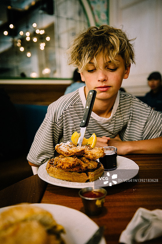 少年男孩看着他的炸鸡和华夫饼的巨型早餐图片素材