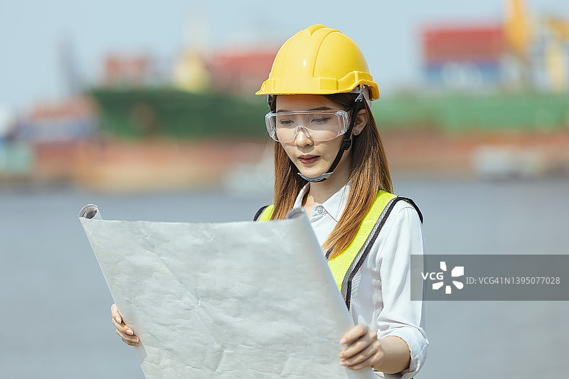 在建筑工地或船厂阅读资料纸或蓝图，了解船舶或工程师行业概念。图片素材