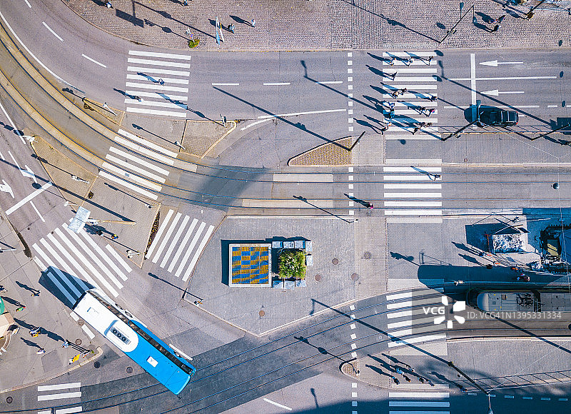 芬兰赫尔辛基，一辆公交车、一辆有轨电车和行人在人行横道上的一个城市十字路口的自上而下视图图片素材