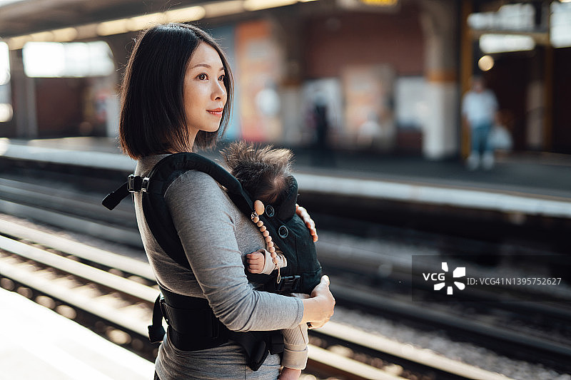 母亲带着孩子在站台上等火车图片素材