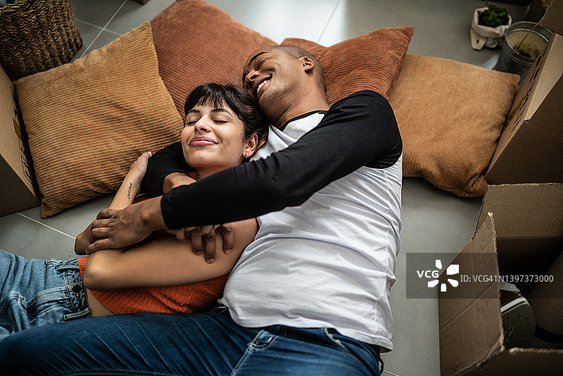 幸福的年轻夫妇躺在新家的地板上图片素材