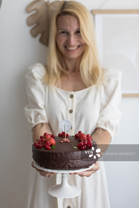 女人拿着巧克力生日蛋糕和浆果图片素材