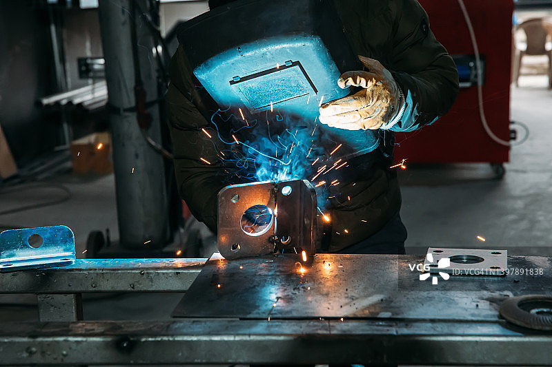工业焊工在工厂里焊接钢铁的工人。图片素材