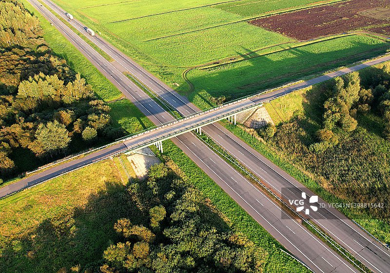 公路沿绿油油的原野设有公路桥和交通交汇处，从空中俯瞰。图片素材