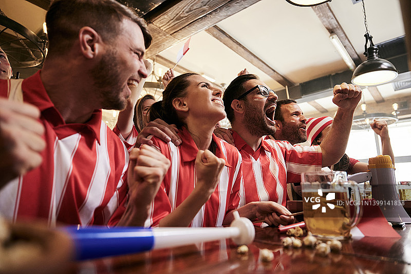 兴高采烈的体育迷们在酒吧里欢呼庆祝他们球队的胜利。图片素材