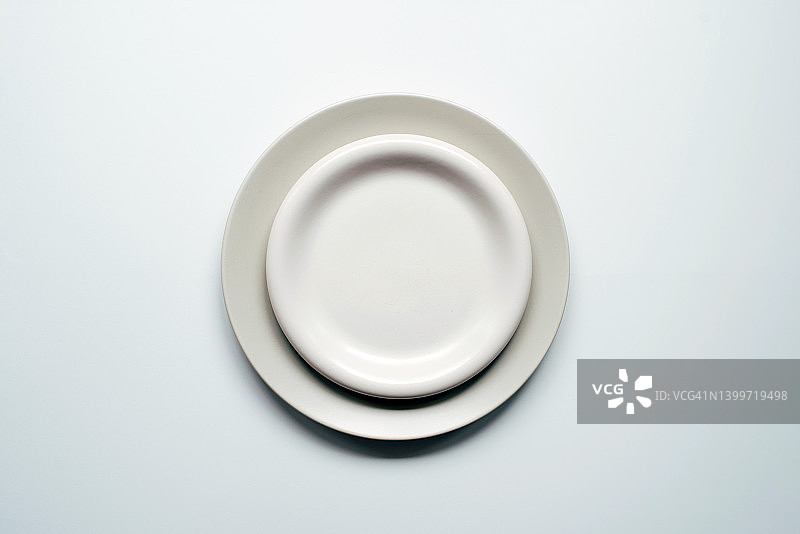 白色背景上放着一个灰白色的盘子。极简主义。空盘子盛食物。烹饪的背景。图片素材