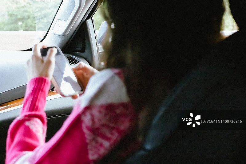年轻的混血女性坐在汽车副驾驶座位上，长发手持黑屏智能手机图片素材
