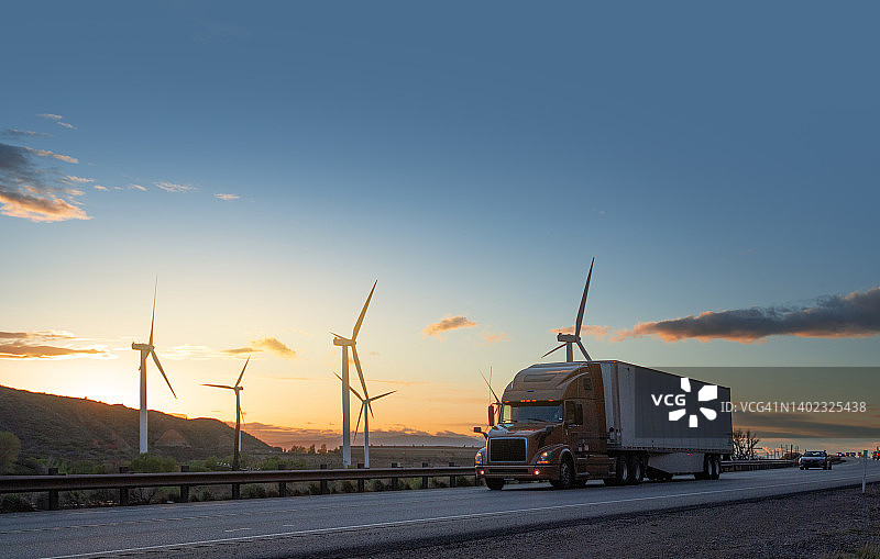 美国犹他州，半卡车在风力涡轮机前超速行驶图片素材