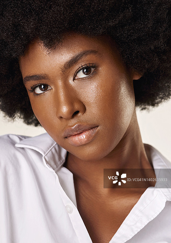 工作室肖像一个年轻迷人的非洲裔美国女人与一个美丽的爆炸头。自信的黑人女模特在灰色背景下展示她光滑的肤色和自然美图片素材