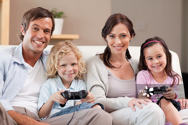 微笑的家人一起玩电子游戏图片素材