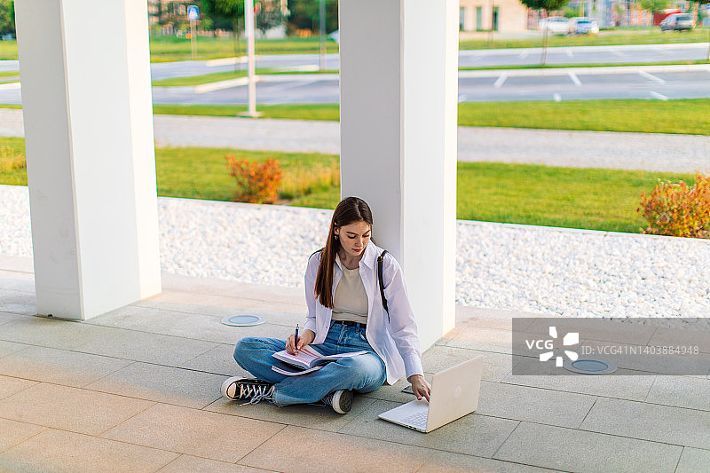 一个女学生正在大学楼前学习图片素材